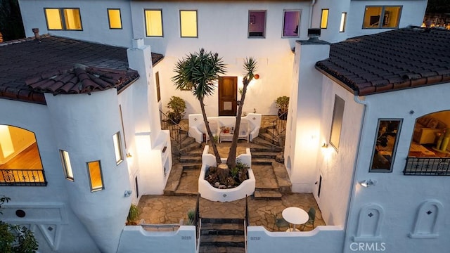 exterior space with a tile roof and stucco siding