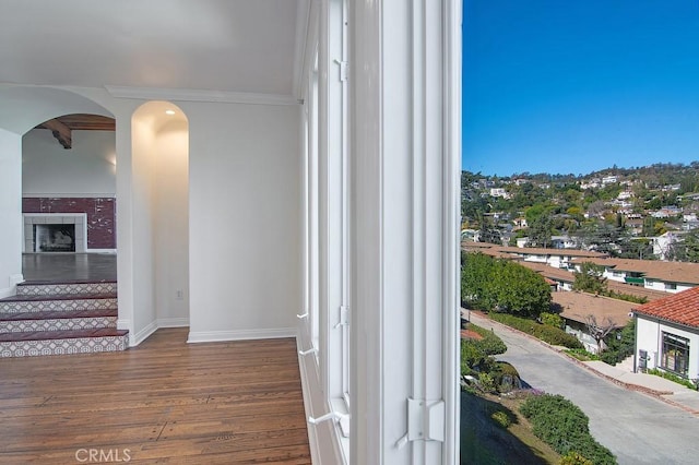 interior space with baseboards, wood finished floors, arched walkways, and ornamental molding
