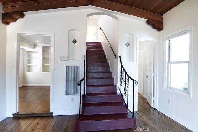 stairway with built in features, wood finished floors, and a healthy amount of sunlight