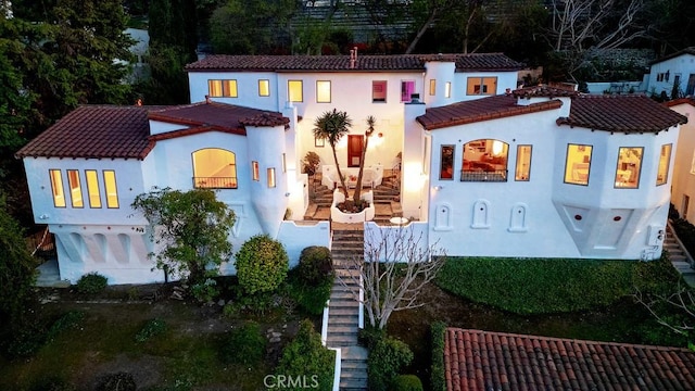 mediterranean / spanish-style house featuring stairway, stucco siding, and a tile roof