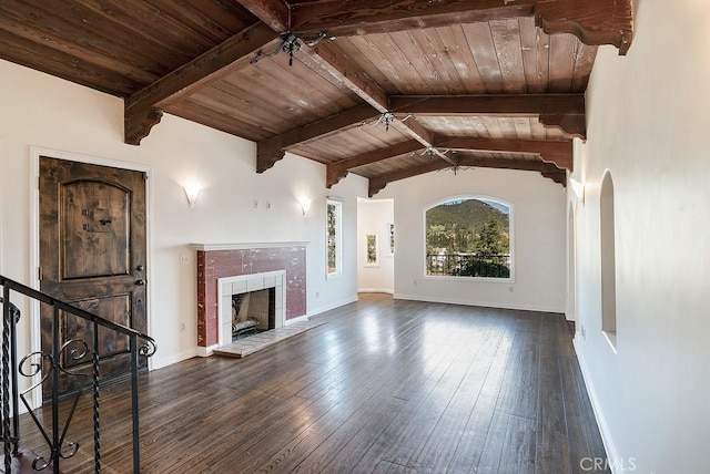 unfurnished living room with vaulted ceiling with beams, baseboards, a tiled fireplace, hardwood / wood-style floors, and wooden ceiling