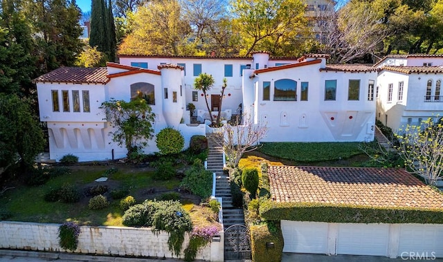 mediterranean / spanish house featuring stairs, a tiled roof, a garage, and stucco siding