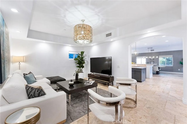 living room with visible vents, a notable chandelier, stone tile flooring, recessed lighting, and baseboards