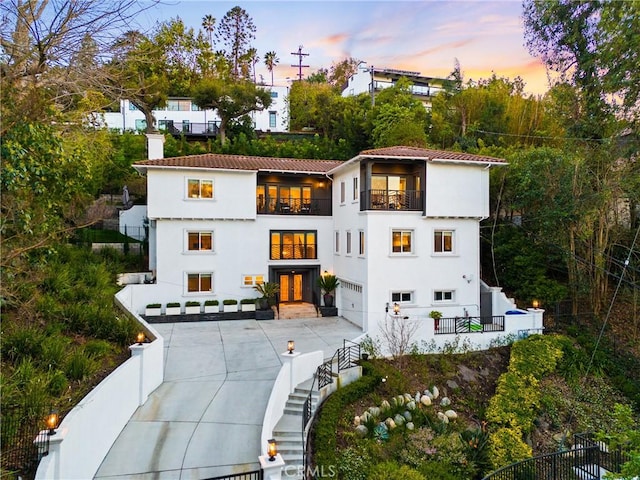 exterior space with a balcony, fence private yard, driveway, and stucco siding