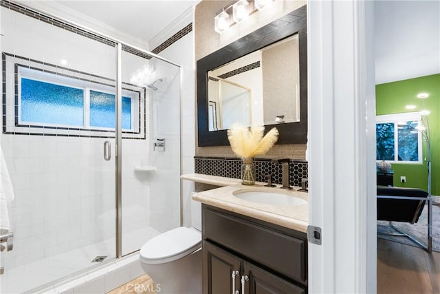 full bathroom with vanity, a stall shower, decorative backsplash, crown molding, and toilet