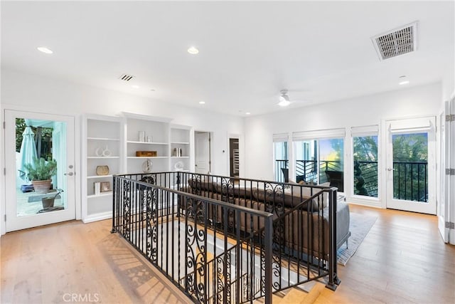 hallway featuring visible vents, an upstairs landing, and wood finished floors