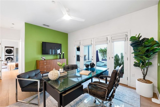 dining room with visible vents, wood finished floors, a ceiling fan, and stacked washer and dryer