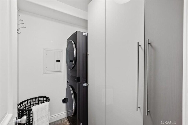 laundry room featuring electric panel, laundry area, and stacked washer and dryer