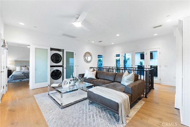 living area with light wood-type flooring, french doors, visible vents, and stacked washing maching and dryer