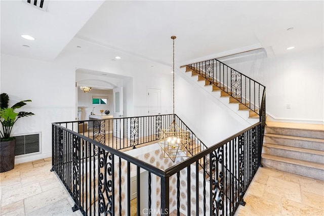 stairway featuring stone tile flooring, recessed lighting, visible vents, and a chandelier