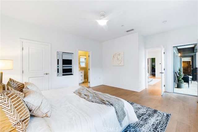 bedroom featuring visible vents, ensuite bathroom, a ceiling fan, wood finished floors, and baseboards