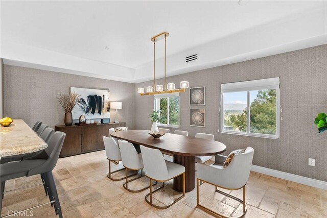 dining room featuring visible vents, baseboards, stone tile floors, an inviting chandelier, and a raised ceiling