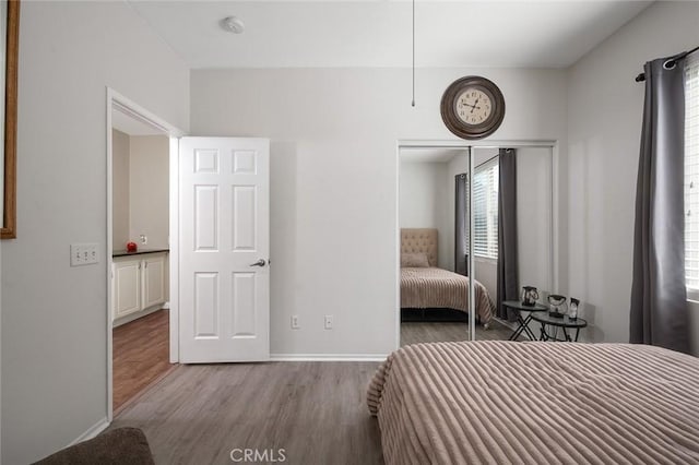 unfurnished bedroom featuring wood finished floors, a closet, and baseboards