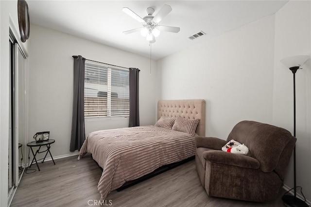 bedroom featuring wood finished floors, baseboards, visible vents, ceiling fan, and a closet