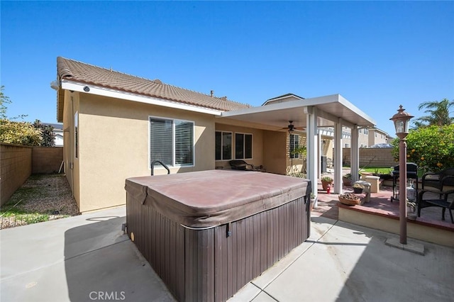 view of patio with ceiling fan, a fenced backyard, and a hot tub