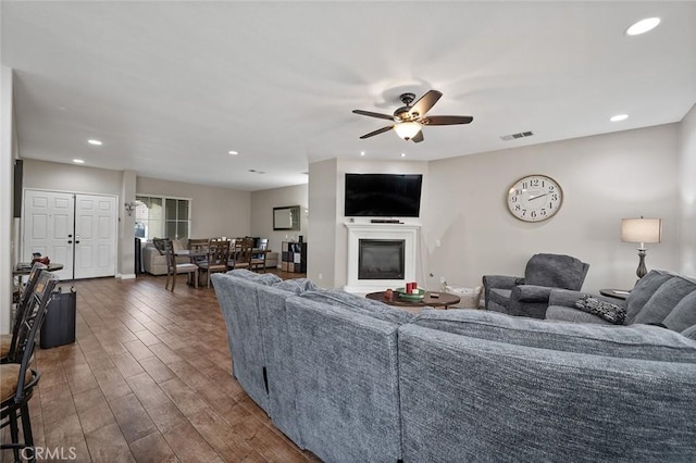 living area with visible vents, recessed lighting, wood finished floors, a glass covered fireplace, and a ceiling fan