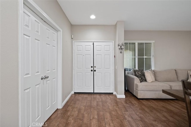 foyer entrance with dark wood-style floors and baseboards