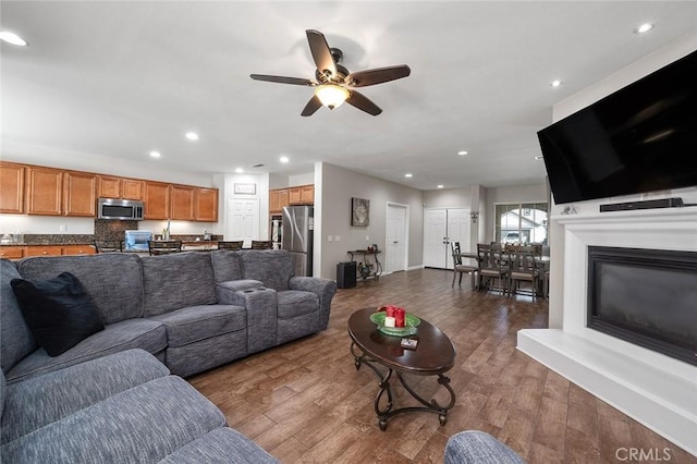 living room featuring recessed lighting, a glass covered fireplace, wood finished floors, and a ceiling fan