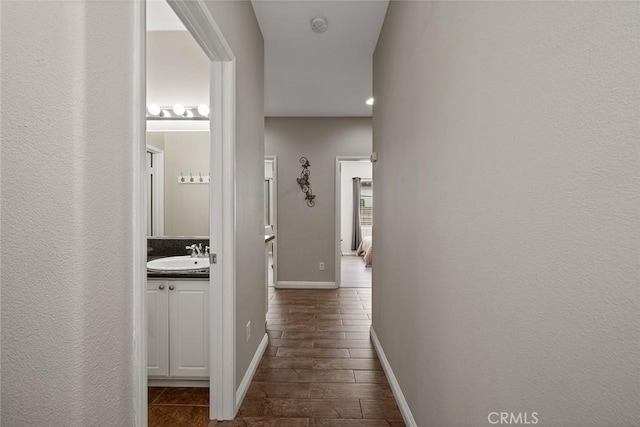 hall featuring baseboards and a sink