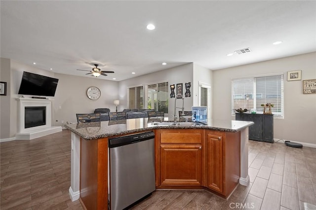 kitchen with visible vents, open floor plan, dishwasher, dark stone counters, and a kitchen island with sink