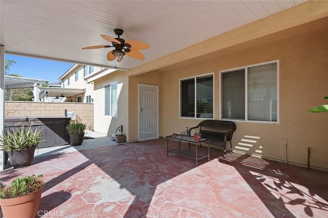 view of patio / terrace with a ceiling fan, fence, and a hot tub