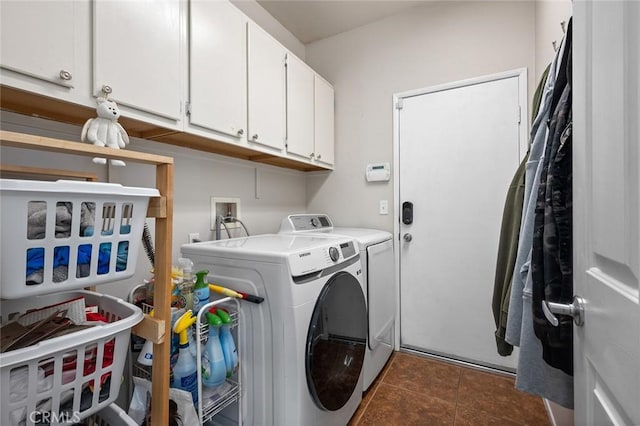 washroom with dark tile patterned floors, cabinet space, and washing machine and dryer