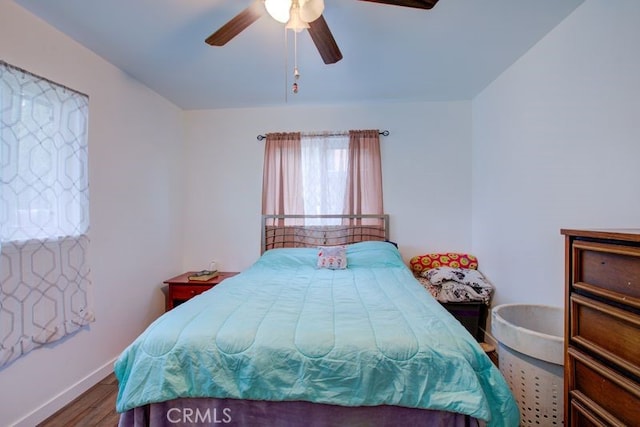 bedroom with a ceiling fan, wood finished floors, and baseboards