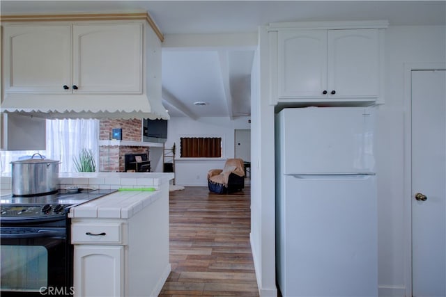 kitchen featuring white cabinetry, tile counters, electric range, and freestanding refrigerator