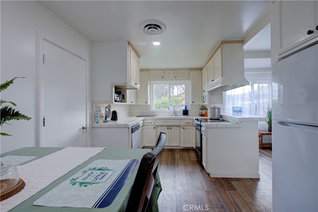 kitchen featuring visible vents, a sink, range with electric stovetop, freestanding refrigerator, and tile countertops