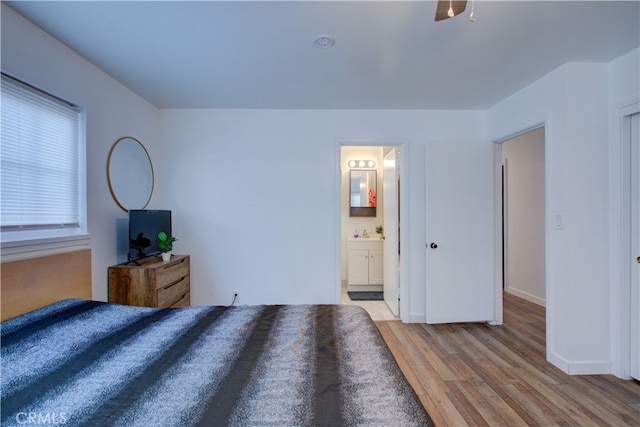 bedroom with light wood-type flooring, baseboards, and ensuite bathroom