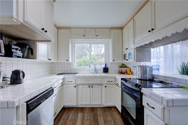 kitchen featuring tile countertops, stainless steel dishwasher, black electric range oven, and a sink