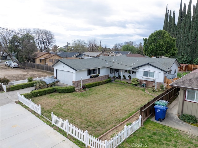 view of front of house featuring a front yard, an attached garage, fence private yard, and driveway