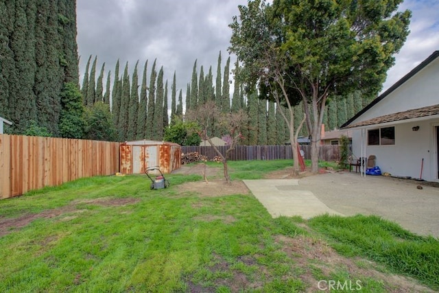 view of yard with an outbuilding, a fenced backyard, a storage shed, and a patio area