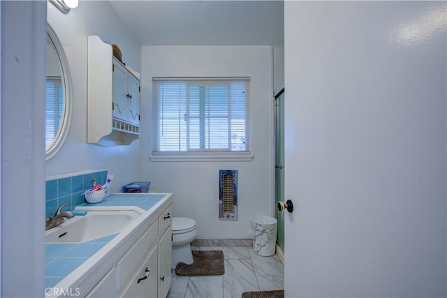 full bath with a shower with shower door, toilet, marble finish floor, heating unit, and vanity