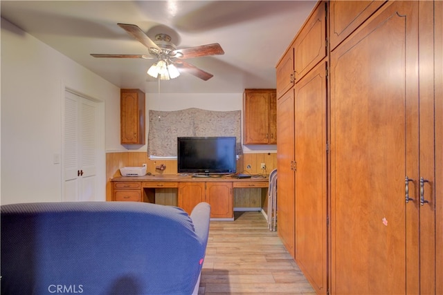 bedroom featuring light wood-style flooring, a ceiling fan, and built in study area