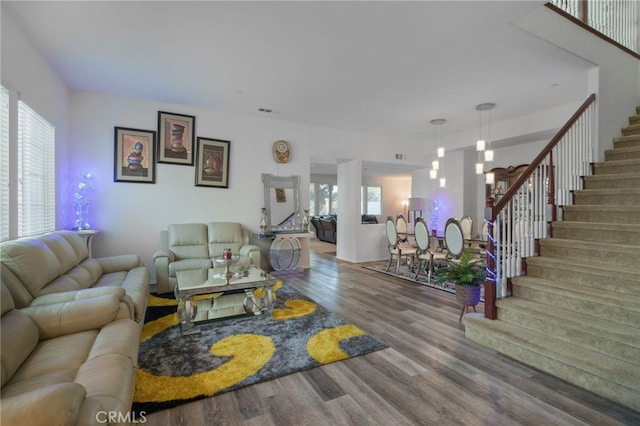 living area featuring stairs, wood finished floors, and a healthy amount of sunlight