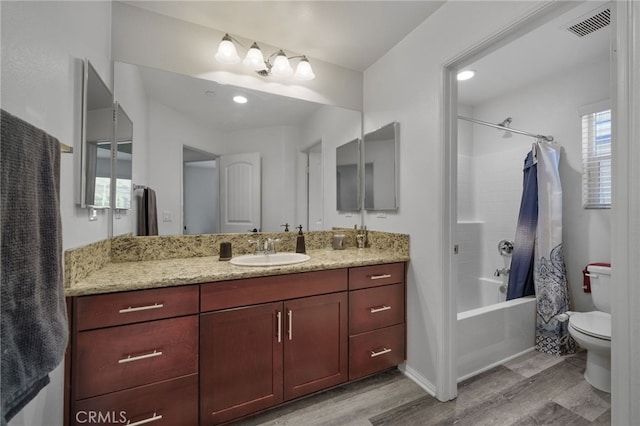 bathroom with visible vents, toilet, wood finished floors, shower / tub combo, and vanity