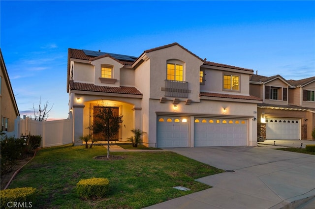 mediterranean / spanish house with solar panels, fence, concrete driveway, stucco siding, and an attached garage