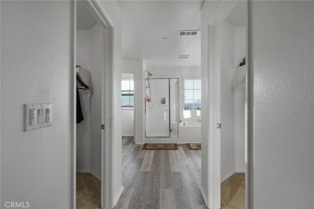 hallway with visible vents, baseboards, and wood finished floors