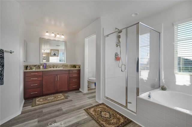 bathroom with toilet, a stall shower, wood finished floors, a bath, and vanity