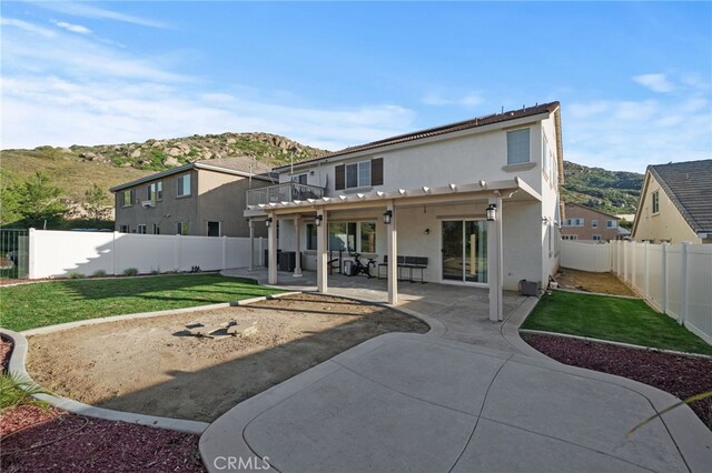 back of property featuring stucco siding, a fenced backyard, a yard, a balcony, and a patio