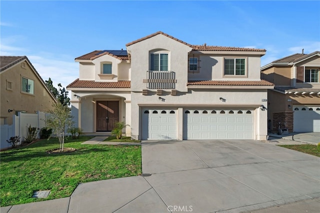 mediterranean / spanish house with fence, a tile roof, concrete driveway, a front yard, and stucco siding