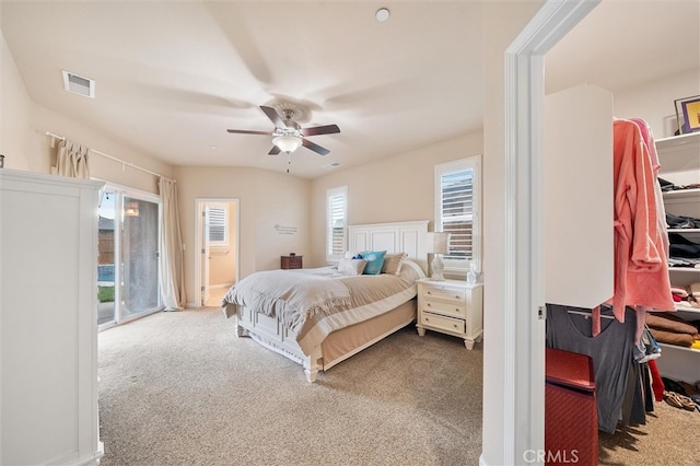 bedroom featuring a spacious closet, visible vents, access to exterior, carpet flooring, and a ceiling fan