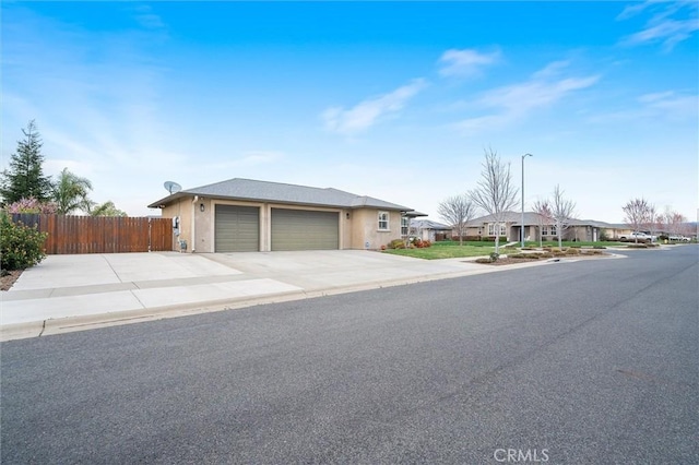 ranch-style house with concrete driveway, an attached garage, and fence