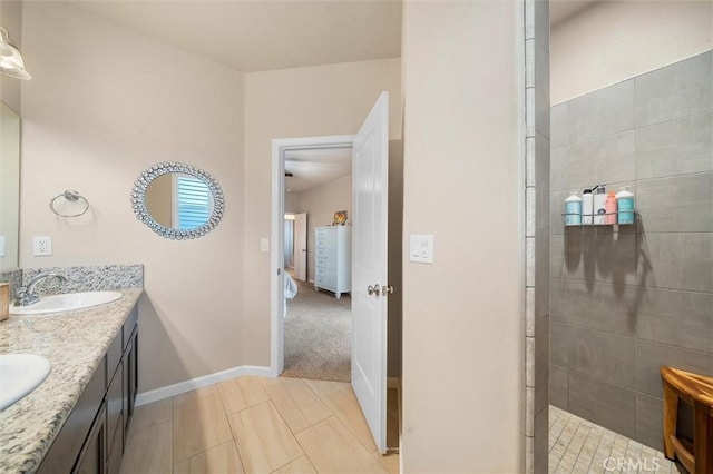 full bathroom with double vanity, baseboards, walk in shower, and a sink