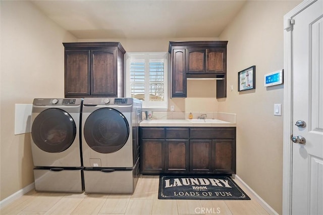 washroom with a sink, baseboards, cabinet space, and washing machine and dryer