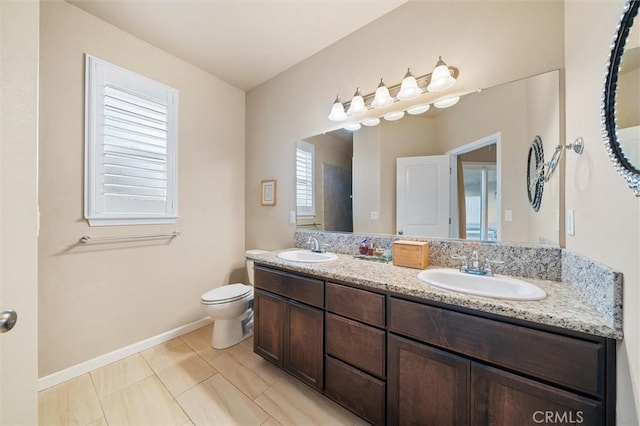 full bathroom with double vanity, toilet, baseboards, and a sink