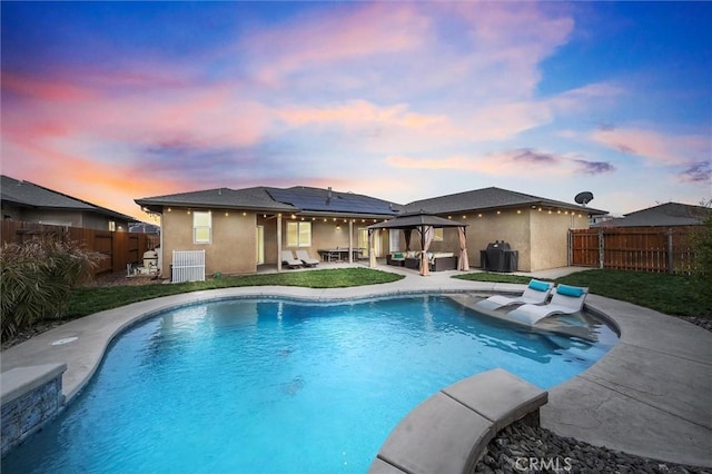 pool at dusk with a gazebo, a patio area, a fenced backyard, and a fenced in pool