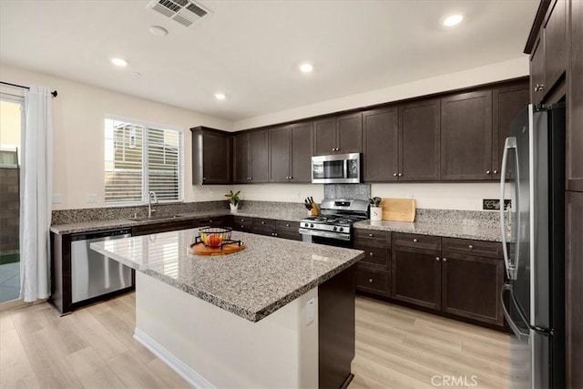 kitchen featuring visible vents, a sink, appliances with stainless steel finishes, light wood finished floors, and dark brown cabinets