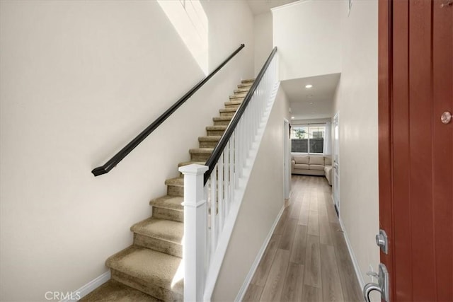 stairway with recessed lighting, baseboards, and wood finished floors